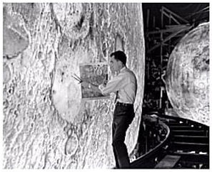 A NASA employee painting detail onto a model of the Moon